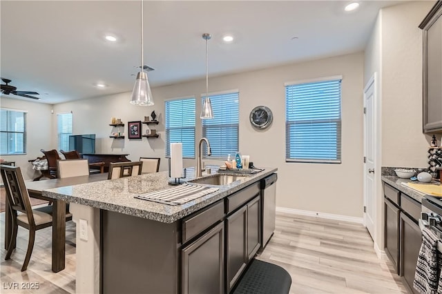 kitchen featuring sink, decorative light fixtures, ceiling fan, stainless steel dishwasher, and a kitchen island with sink