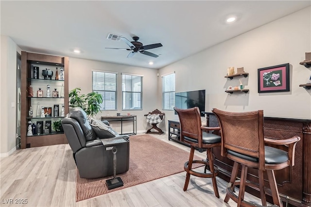 living room with light hardwood / wood-style floors, indoor bar, and ceiling fan