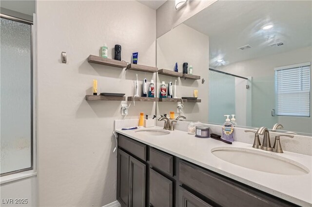 bathroom featuring a shower with door and vanity