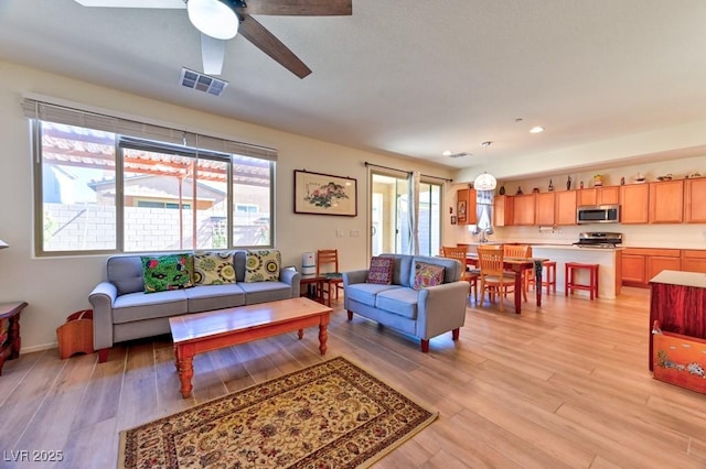 living room with ceiling fan and light wood-type flooring