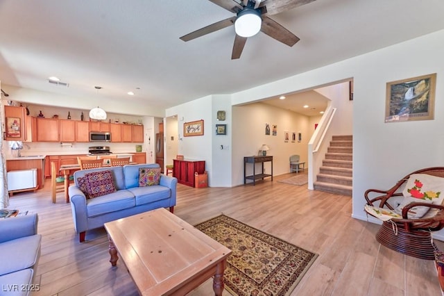 living room featuring ceiling fan, light hardwood / wood-style floors, and sink