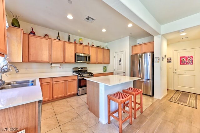 kitchen featuring stainless steel appliances, a center island, sink, and a breakfast bar