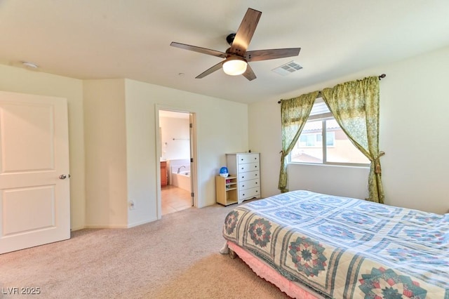 bedroom with ceiling fan, light carpet, and ensuite bath