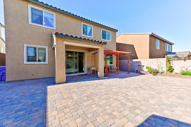 back of property with a pergola and a patio area