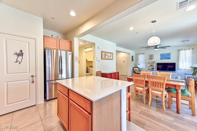 kitchen featuring decorative light fixtures, a center island, ceiling fan, and stainless steel fridge