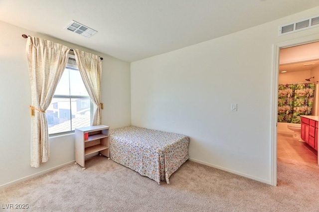 bedroom with ensuite bath and light colored carpet