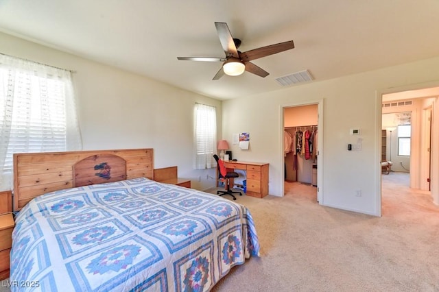 carpeted bedroom featuring a walk in closet, ceiling fan, a closet, and multiple windows