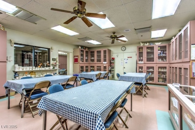 recreation room featuring a drop ceiling and ceiling fan