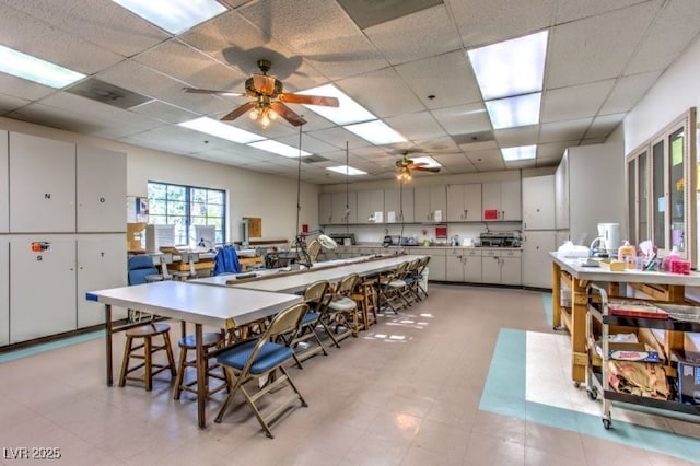 dining space with a drop ceiling and ceiling fan