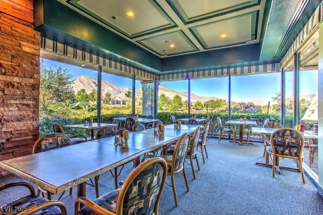 sunroom featuring coffered ceiling, plenty of natural light, and a mountain view