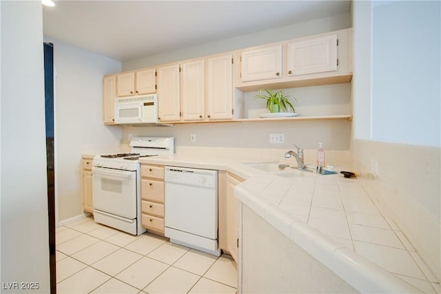 kitchen featuring white appliances, light tile patterned floors, tile counters, and sink