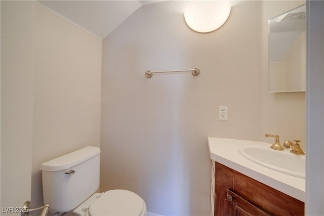 bathroom featuring toilet, vanity, and vaulted ceiling