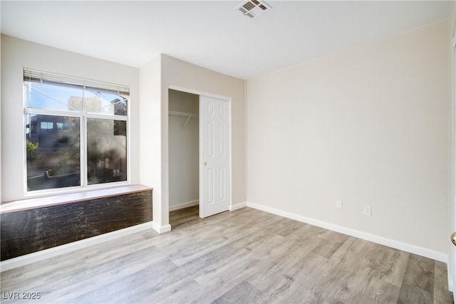 unfurnished bedroom with light hardwood / wood-style flooring and a closet