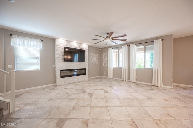 unfurnished living room with light tile patterned flooring, ceiling fan, and a stone fireplace