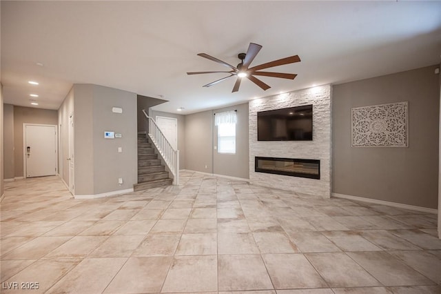 unfurnished living room featuring ceiling fan and a stone fireplace