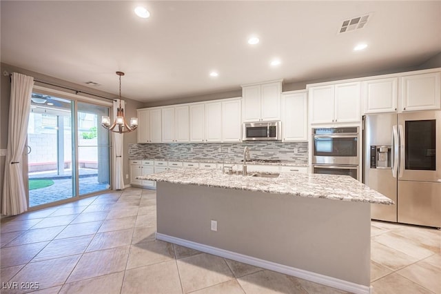 kitchen featuring white cabinets, stainless steel appliances, an island with sink, light stone countertops, and sink