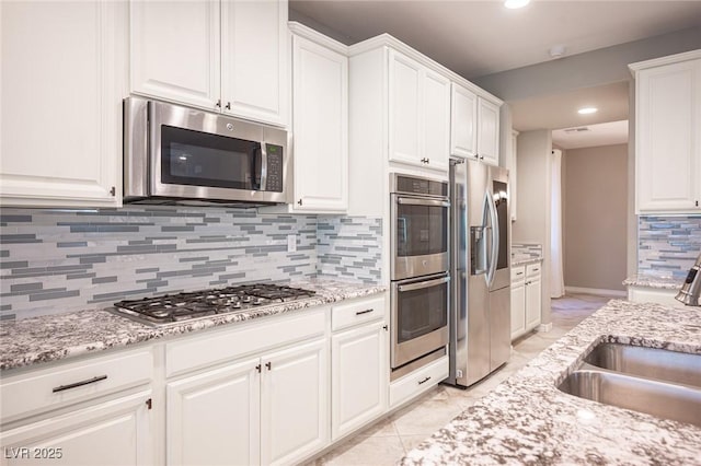 kitchen featuring white cabinets, appliances with stainless steel finishes, decorative backsplash, and sink