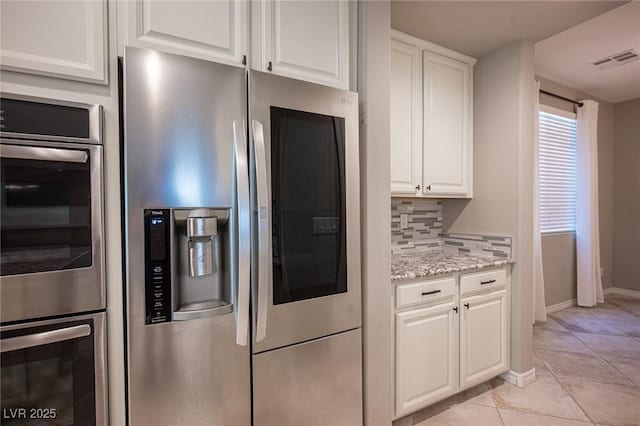 kitchen featuring stainless steel appliances, white cabinets, decorative backsplash, and light stone counters