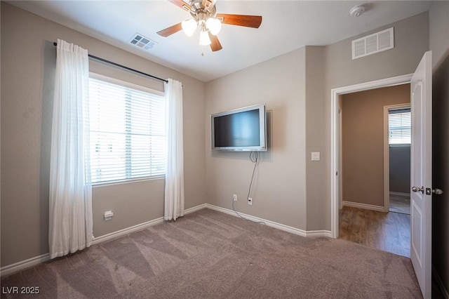 carpeted spare room featuring ceiling fan and plenty of natural light