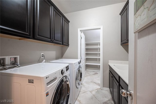 laundry area with a textured ceiling, cabinets, washer and clothes dryer, and sink