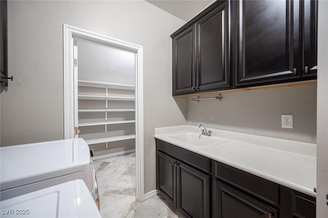 laundry area with cabinets, washing machine and clothes dryer, and sink