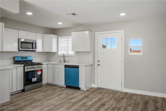 kitchen featuring light hardwood / wood-style flooring, sink, backsplash, white cabinets, and stainless steel appliances