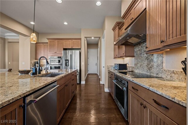 kitchen with appliances with stainless steel finishes, hanging light fixtures, light stone counters, and sink