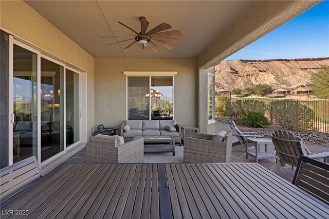 wooden deck featuring a patio area, ceiling fan, an outdoor living space, and a mountain view