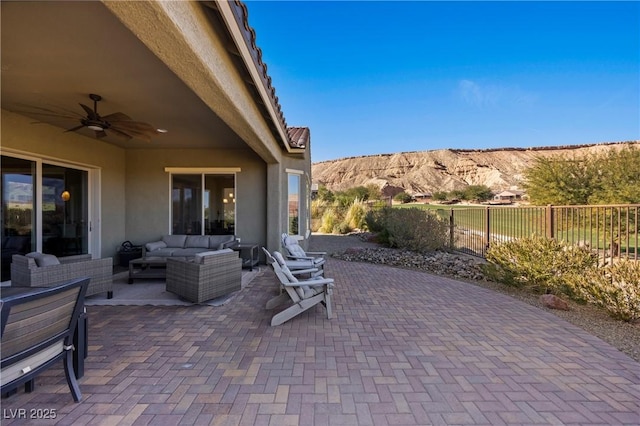 view of patio with ceiling fan, an outdoor hangout area, and a mountain view