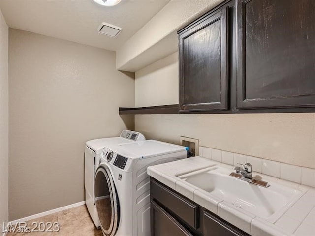 laundry area with light tile patterned flooring, cabinets, washing machine and clothes dryer, and sink