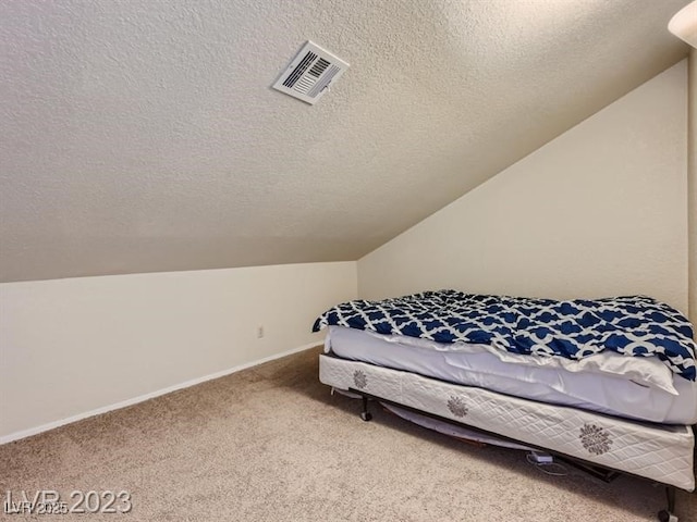 carpeted bedroom with a textured ceiling and lofted ceiling