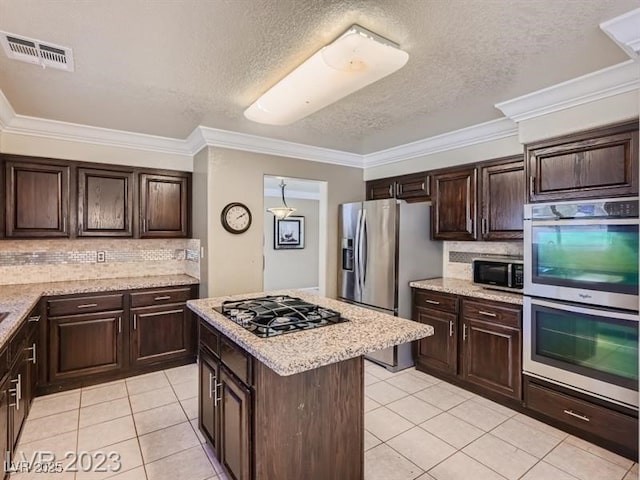 kitchen with appliances with stainless steel finishes, light tile patterned floors, and dark brown cabinets