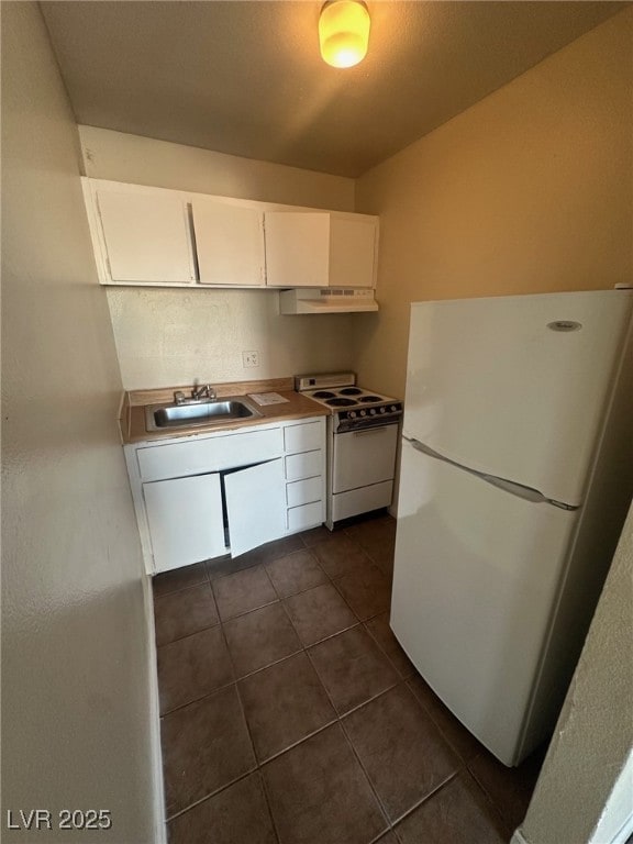 kitchen with white appliances, white cabinetry, dark tile patterned floors, and sink