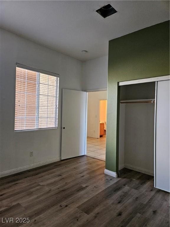 unfurnished bedroom with dark hardwood / wood-style flooring and a closet