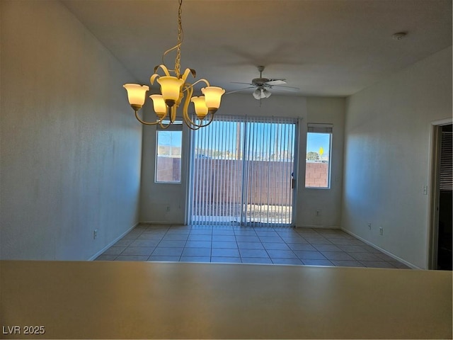 tiled spare room with ceiling fan with notable chandelier