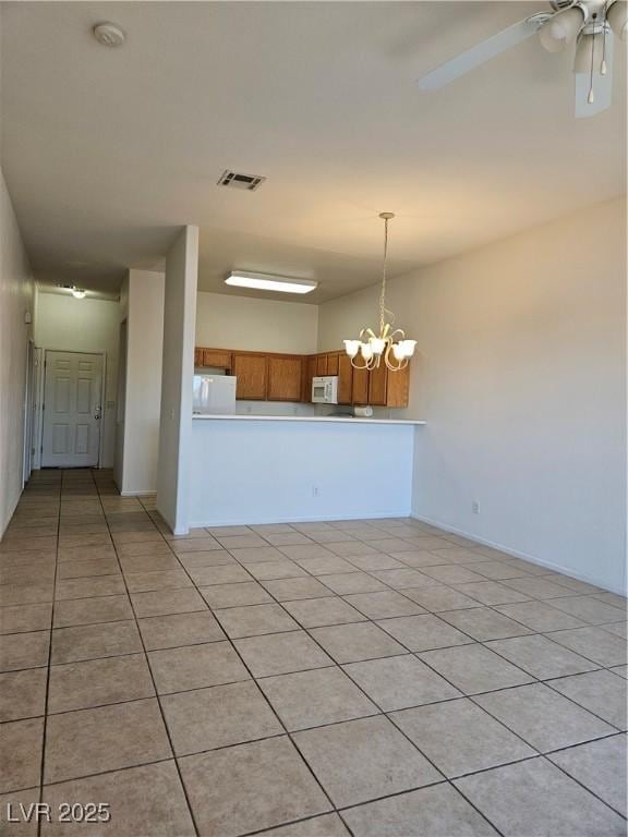 kitchen featuring white appliances, light tile patterned floors, pendant lighting, and ceiling fan with notable chandelier