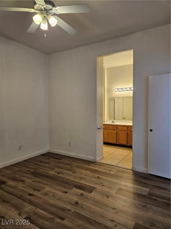 unfurnished bedroom with ensuite bathroom, light wood-type flooring, and ceiling fan