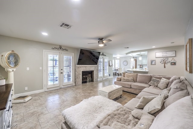 living room with french doors, a tile fireplace, and ceiling fan