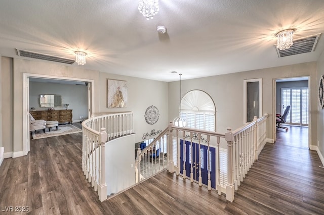 corridor with a textured ceiling, a chandelier, and dark hardwood / wood-style floors