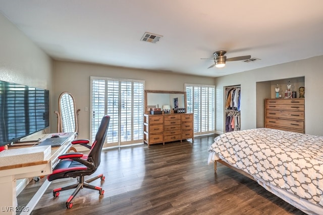 bedroom with ceiling fan, dark wood-type flooring, a closet, and a walk in closet