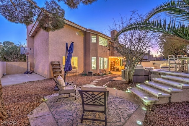 back house at dusk featuring a patio