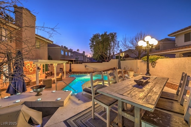 pool at dusk with a patio and an outdoor hangout area