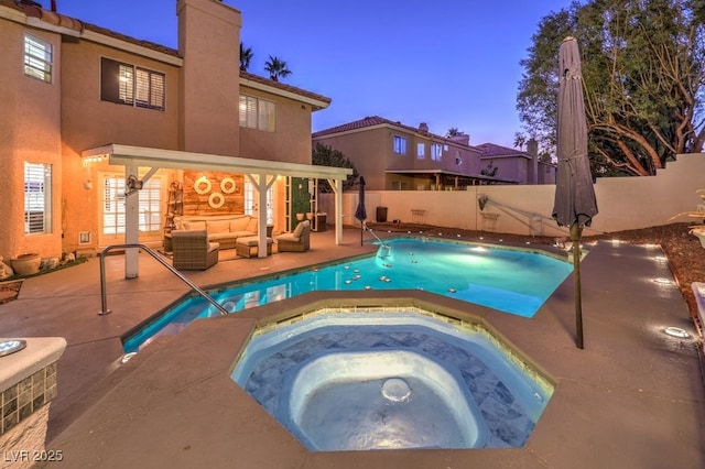 pool at dusk featuring a patio, an outdoor hangout area, and an in ground hot tub