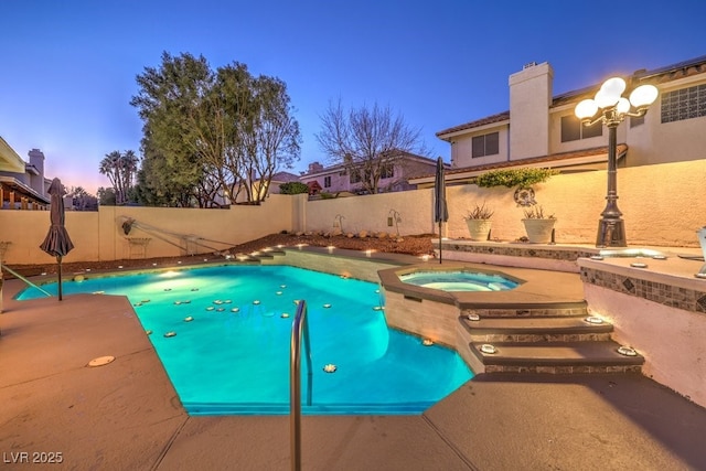 pool at dusk featuring an in ground hot tub