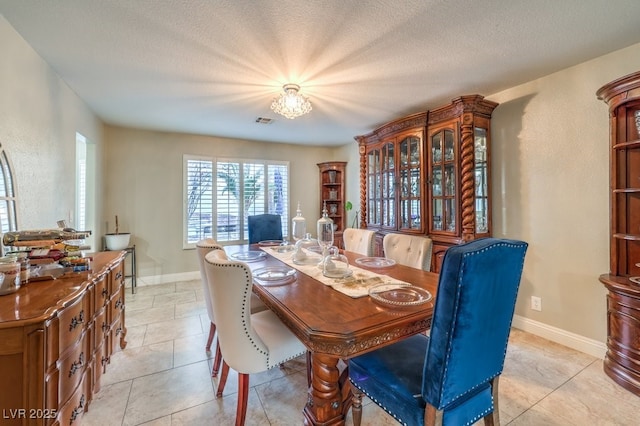 dining area with light tile patterned flooring, a textured ceiling, and an inviting chandelier