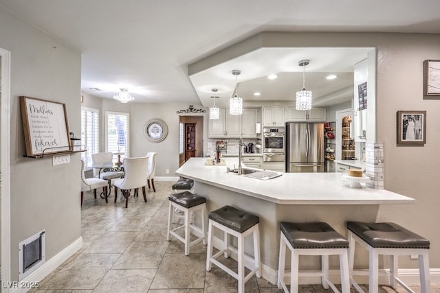 kitchen with stainless steel appliances, a kitchen bar, sink, and pendant lighting