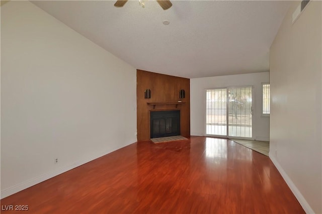 unfurnished living room featuring ceiling fan, a large fireplace, and hardwood / wood-style floors