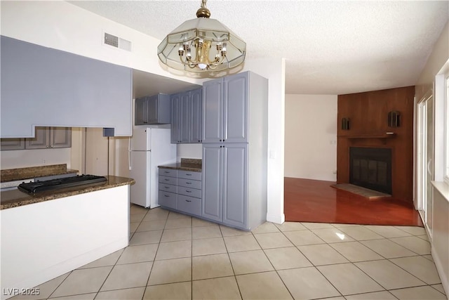 kitchen with white refrigerator, gray cabinets, light tile patterned floors, and a fireplace