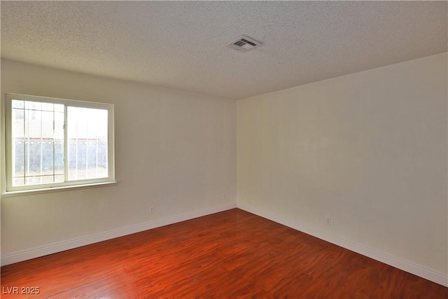 spare room with hardwood / wood-style floors and a textured ceiling