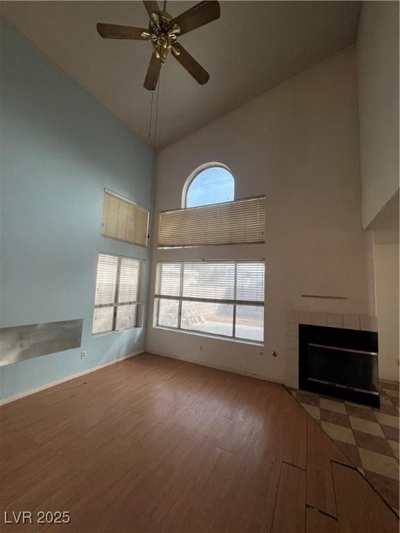 unfurnished living room with ceiling fan, hardwood / wood-style floors, a fireplace, and high vaulted ceiling